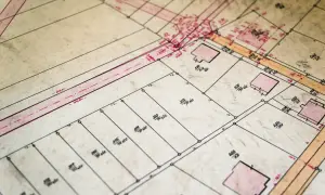 Stary plan geodezyjny z zaznaczonymi numerami działek i budynkami. Każdy identyfikator działki ewidencyjnej jest wyraźnie widoczny.