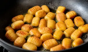 Gnocchis dorés et légèrement grillés dans une poêle, prêts pour la cuisson finale.