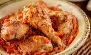 Pollo alla cacciatora ricetta della nonna: succulenti pezzi di pollo in un ricco sugo di pomodoro e erbe aromatiche, serviti in una ciotola rustica.