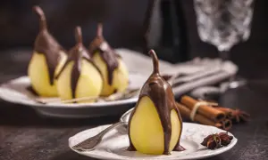 Poires pochées nappées de chocolat, un délice de poire belle Hélène. Cannelle et anis étoilé en arrière-plan.