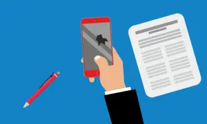 Rękojmia a gwarancja: ręka trzyma pęknięty telefon, obok dokument i długopis.