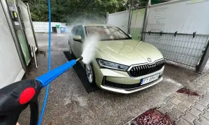 Usuwanie żywicy z lakieru: mycie auta na myjni bezdotykowej. Woda pod ciśnieniem spływa po masce.
