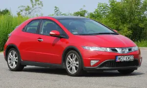 Czerwony Honda Civic 8 z czarnym dachem, zaparkowany na drodze. Widać przednie światła i grill.