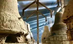 Forni antichi nel paese delle campane Molise, con raggi di luce che illuminano la polvere e le forme grezze delle campane in attesa di essere fuse.