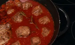 Stracotto di manzo schmort in einer tiefroten Sauce mit Rosmarin. Zarte Fleischstücke, perfekt für ein herzhaftes Gericht.