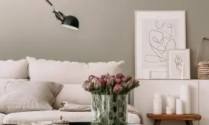 Gemütliches Wohnzimmer mit skandinavischen Wandfarben, einem Sofa mit Leinenkissen, Tulpen und minimalistischer Kunst.
