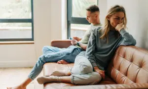 Een vrouw denkt diep na, terwijl een man op zijn telefoon kijkt. Het lijkt erop dat opposites attract betekenis hier niet opgaat.