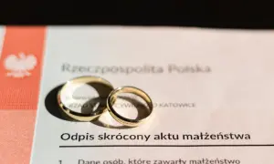 Złote obrączki na odpisie skróconym aktu małżeństwa, symbolizujące związek.