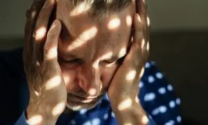 Uomo con le mani sulla testa, illuminato da fasci di luce che creano un effetto di **blocco emotivo test**.