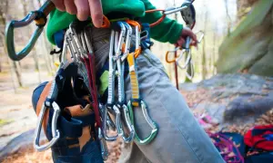 Kletterer mit Ausrüstung, darunter Kletterschuhe und Karabiner, bereit für die selbstsicherung beim Klettern.
