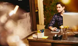 Uomo al computer, con sfondo di muschio. Potrebbe essere un annuncio per un job posting interno.