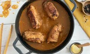 Herzhafte schweinerouladen nach omas rezept in dunkler Soße, bereit zum Servieren. Daneben Senf, Salz und Pfeffer.