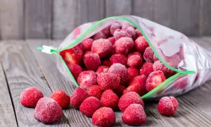 Mrożone truskawki wysypują się z otwartej torebki. Idealne, by rozmrażać truskawki do galaretki.