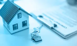 Modellino di casa, chiavi con ciondolo a forma di casa e documenti pronti per vendere casa.