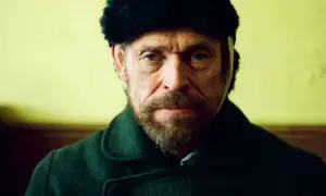 Willem Dafoe w czapce z futra i ciemnym płaszczu, w kadrze z filmu.