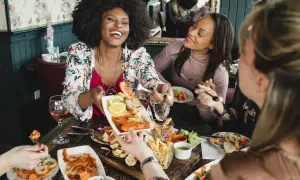 Vier Freundinnen genießen einen köstlichen Brunch in Berlin. Sie lachen und teilen sich Speisen wie Garnelen und Pommes.