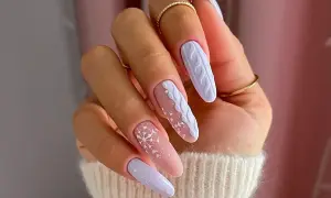 Manucure d'hiver avec des flocons de neige et un motif de pull tricoté sur des ongles longs. Un modèle ongle hiver parfait pour la saison.