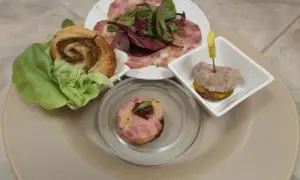 Verschiedene Tapas mit Fleisch: ein Fleischröllchen im Blätterteig, ein kleiner Burger mit Fleisch und ein Stück Fleischpastete.