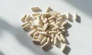 Kapsułki probioset rozsypane na białym tle, oświetlone słońcem.