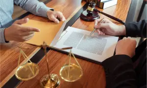 Prawnik doradza, jak wybrnąć ze skargi pauliańskiej. Na stole dokumenty, waga sprawiedliwości i młotek sędziowski.