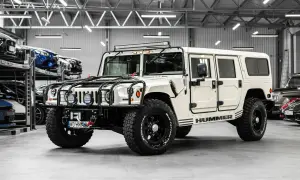 Biały Hummer H1 z potężnymi oponami i dodatkowym oświetleniem na dachu, gotowy na każdą przygodę.