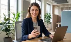 Donna sorridente al telefono, con un laptop aperto. Sembra che stia organizzando la sua astensione dal lavoro.
