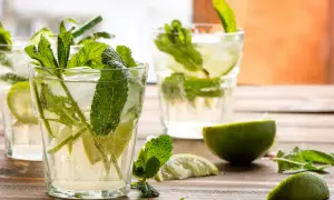 Verre de mojito frais avec menthe, citron vert et glaçons. Parfait pour une recette mojito rafraîchissante.
