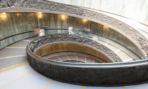 Watykańska, spiralna klatka schodowa z bogatymi zdobieniami, gdzie ludzie spieszą na audiencję u papieża.