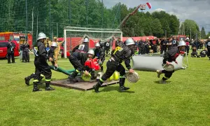 Strażacy w akcji podczas zawodów OSP bojówka. Drużyny zmagają się z zadaniami, rozwijając węże i pompując wodę.