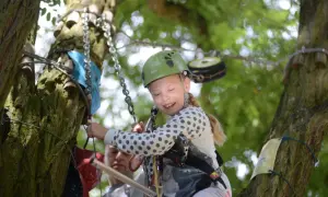 Uśmiechnięta dziewczynka w kasku na ściężce linowej w Łagowie. Wspaniałe łagów atrakcje dla dzieci!