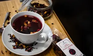 Aromatyczna herbata owocowa w filiżance, obok słoik z suszem i paczka z napisem "Dzień gorącego lata". Ile kcal ma herbata owocowa? Zazwyczaj niewiele!