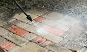Mycie kostki brukowej myjką ciśnieniową. Woda pod ciśnieniem skutecznie usuwa brud, pokazując, czym wyczyścić kostkę brukową.