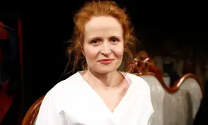 Dominika Kluźniak w białej koszuli, aktorka znana z filmów, seriali i programów, uśmiecha się lekko.