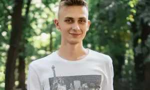 Uśmiechnięty nastolatek w białej koszulce z widokiem na Nowy Jork. Może to być przykład, jak zespół Aspergera objawy u nastolatków mogą być subtelne.