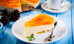 Pyszny sernik na zimno z brzoskwiniami, udekorowany galaretką i owocami. Idealny deser na letnie dni.