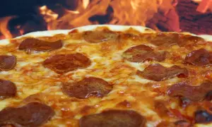Pyszna pepperoni pizza z ciągnącym się serem, pieczona w ogniu.