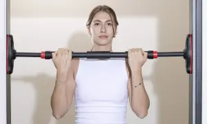 Frau hält Klimmzugstange Türrahmen Test. Einfache Montage für das Training zu Hause.