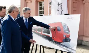 Dwóch mężczyzn w garniturach ogląda wizualizację nowego pociągu Kolei Wielkopolskich. Nowe połączenia Poznań - Nowy Tomyśl wkrótce!