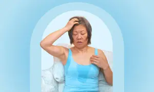 A woman experiencing night sweats after working out, with sweat visible on her tank top and forehead.