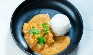 En krämig butter chicken med ris, garnerad med färsk koriander. En smakrik indisk rätt.