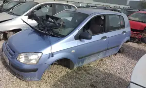 Desguace de un Hyundai Getz 1.1. El coche está en un desguace, sin ruedas y con partes rotas, evidenciando sus problemas.