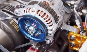 Detalle de un alternador de coche, listo para cambiar. Se aprecian la polea azul y la correa.