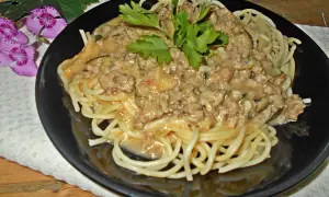 Pyszny makaron z mięsem mielonym w sosie śmietanowym, udekorowany natką pietruszki. Idealny na szybki obiad.