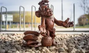 Figurka krasnala z beczką i workami, jeden z lwy gdańskie, stoi na kamieniach przed stadionem.