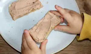 Kind hält Brot mit Leberwurst. Ab wann Leberwurst Baby? Erste Kostprobe für den Nachwuchs.