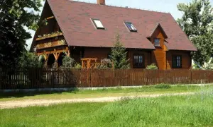 Działka siedliskowa co to znaczy? Drewniany dom z werandą i ogrodem, otoczony płotem, idealny na spokojne życie na wsi.