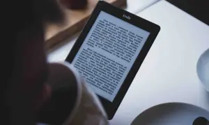 Osoba czyta książkę w formacie kindle. Na ekranie widoczny jest tekst powieści.