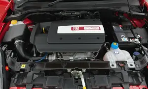 Silnik MultiAir Turbo w Fiat Grande Punto 1.4. Widoczny jest czarny plastikowy dekiel z logo Fiata, akumulator i zbiornik płynu chłodniczego.