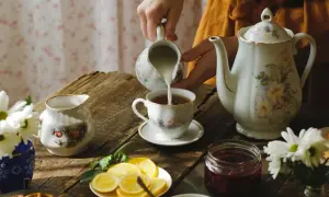 Chwila relaksu przy herbacie, tak o której Anglicy piją herbatę. Mleko wlewane do filiżanki, obok dzbanek, cytryny i dżem.