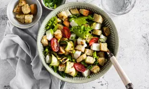 Deliziosa insalata di zucchine grigliate, pomodorini, cubetti di formaggio fresco e crostini croccanti, guarnita con erba cipollina.